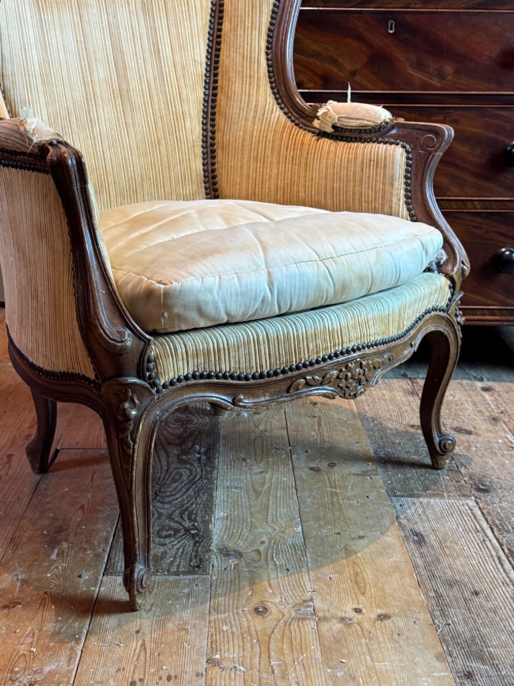 A Louis XV style bergere armchair featuring a carved dark wooden frame, enclosed upholstered arms, beige fabric, and cabriole legs. View VI