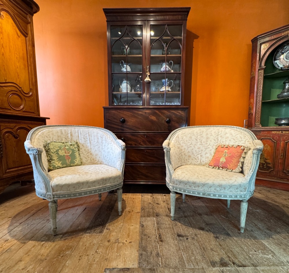 A pair of French tub armchairs featuring distressed cream painted carved wooden frames and light floral upholstery. View II
