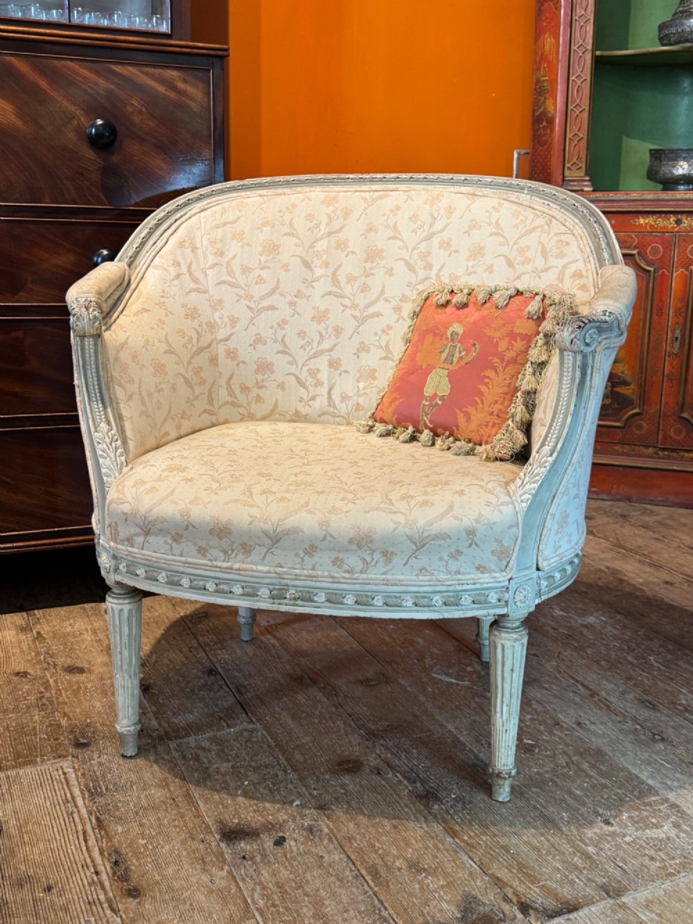 A pair of French tub armchairs featuring distressed cream painted carved wooden frames and light floral upholstery. View VI
