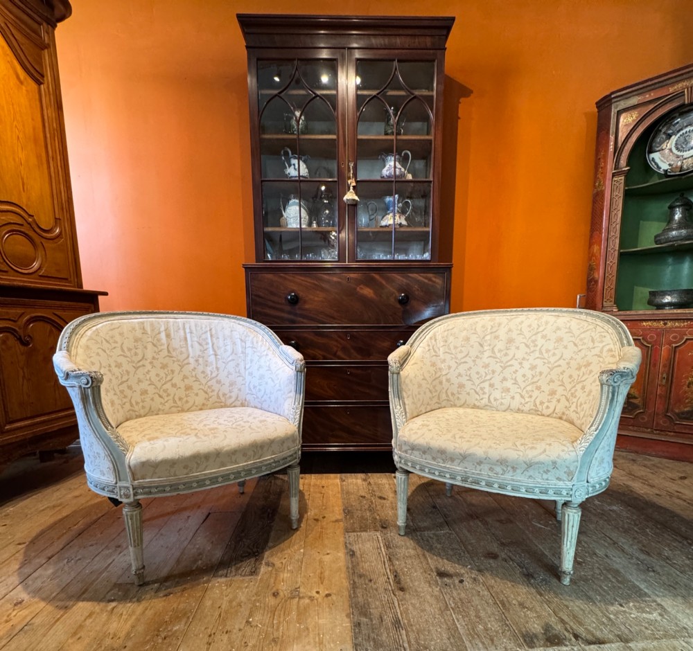 A pair of French tub armchairs featuring distressed cream painted carved wooden frames and light floral upholstery. View VII