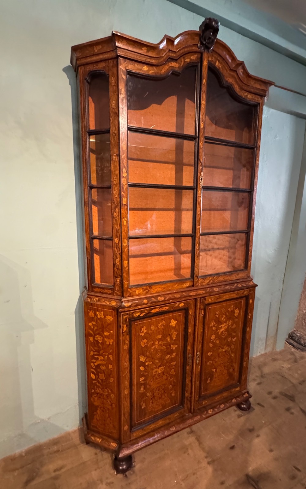 An antique Dutch walnut display cabinet featuring intricate floral marquetry inlays, glazed upper doors, and a double cupboard lower section supported by bun feet. View II