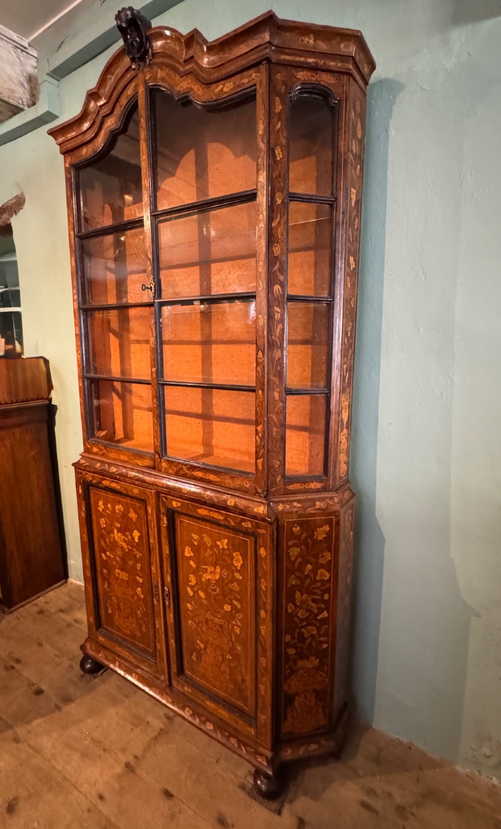 An antique Dutch walnut display cabinet featuring intricate floral marquetry inlays, glazed upper doors, and a double cupboard lower section supported by bun feet. View VIII