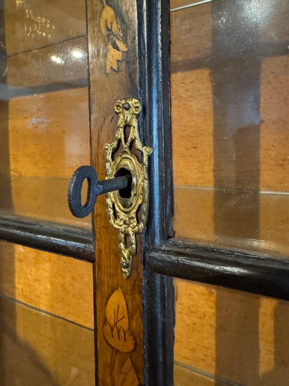 An antique Dutch walnut display cabinet featuring intricate floral marquetry inlays, glazed upper doors, and a double cupboard lower section supported by bun feet. View IX