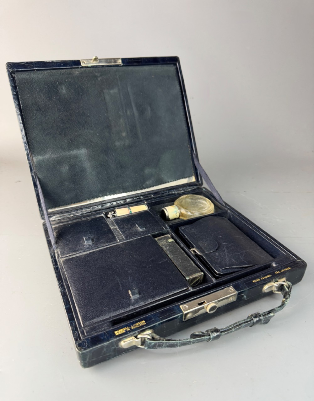 A black crocodile leather rectangular vanity case featuring a curved front flap pocket, top handle, and brass clasp. View III