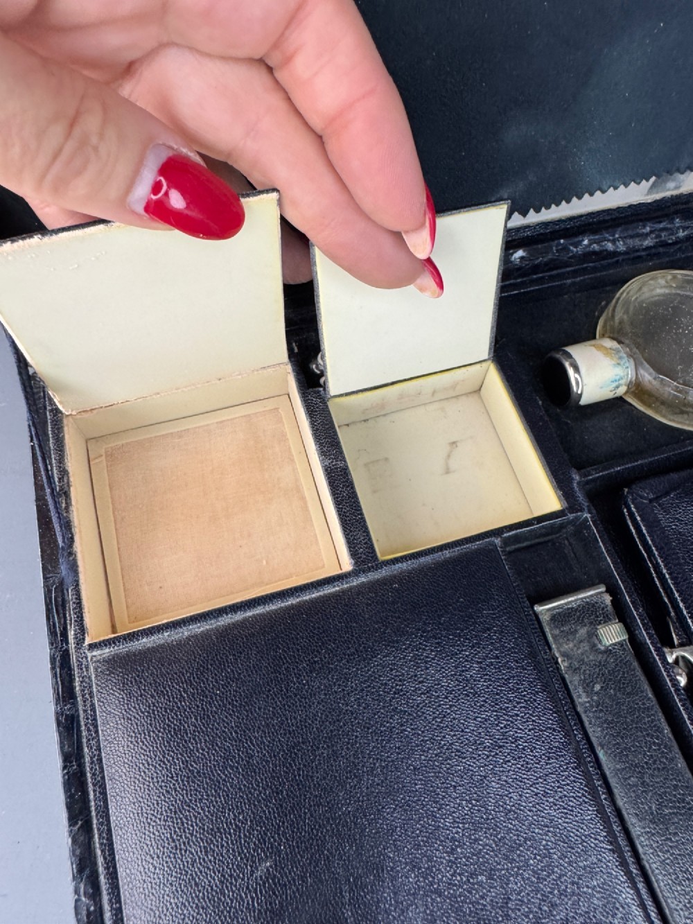 A black crocodile leather rectangular vanity case featuring a curved front flap pocket, top handle, and brass clasp. View IX