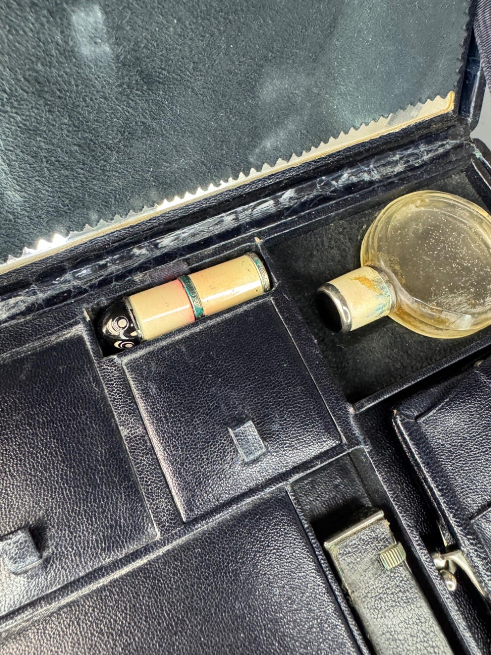 A black crocodile leather rectangular vanity case featuring a curved front flap pocket, top handle, and brass clasp. View X