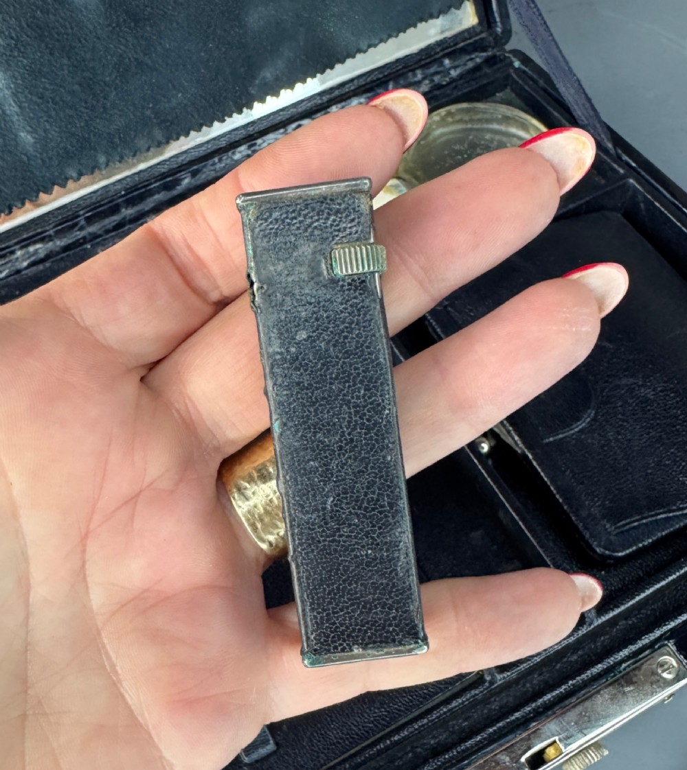 A black crocodile leather rectangular vanity case featuring a curved front flap pocket, top handle, and brass clasp. View XI