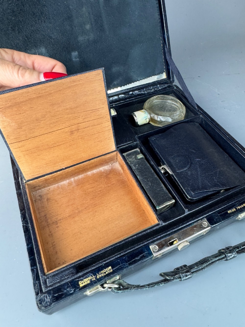 A black crocodile leather rectangular vanity case featuring a curved front flap pocket, top handle, and brass clasp. View XII