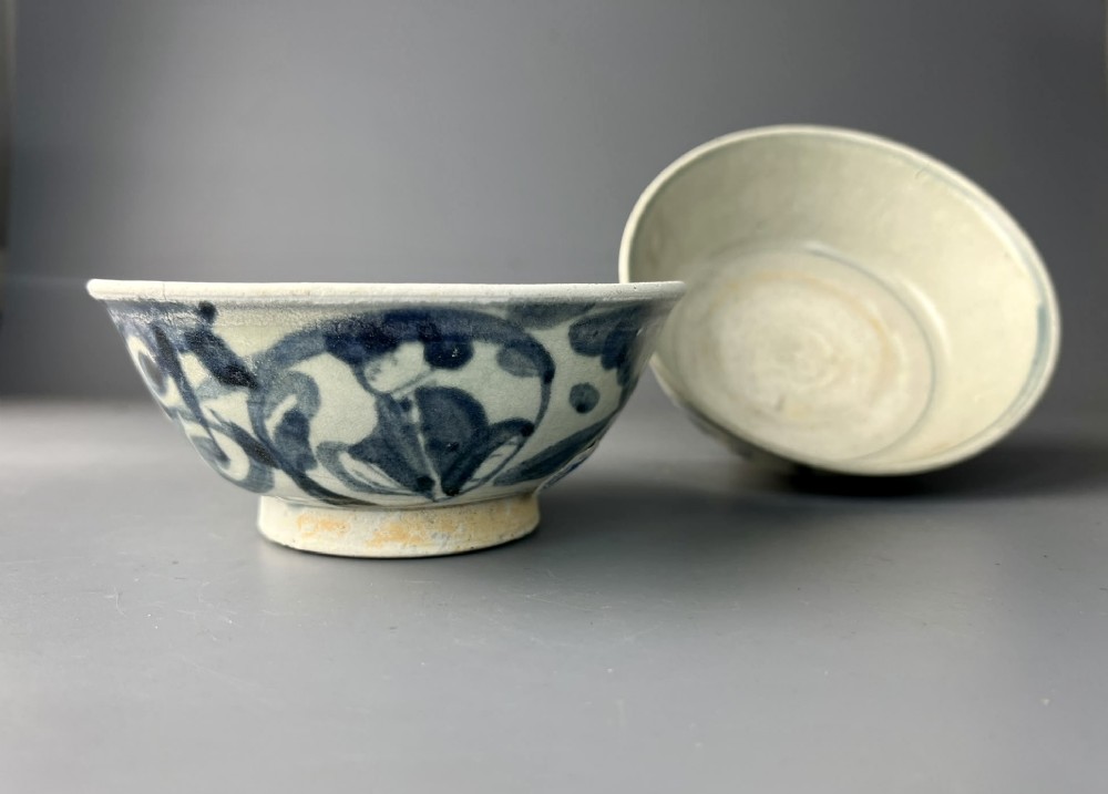 A pair of 17th-century Chinese shipwreck porcelain bowls featuring hand-painted cobalt blue swirling patterns over an off-white background. View II