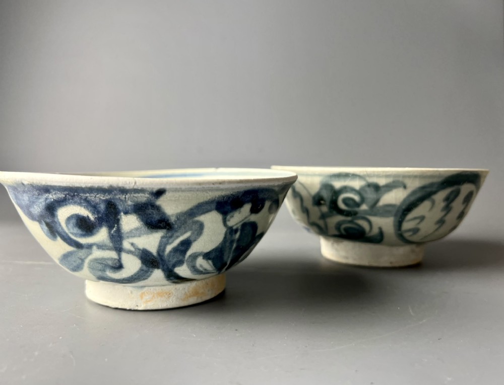 A pair of 17th-century Chinese shipwreck porcelain bowls featuring hand-painted cobalt blue swirling patterns over an off-white background. View III