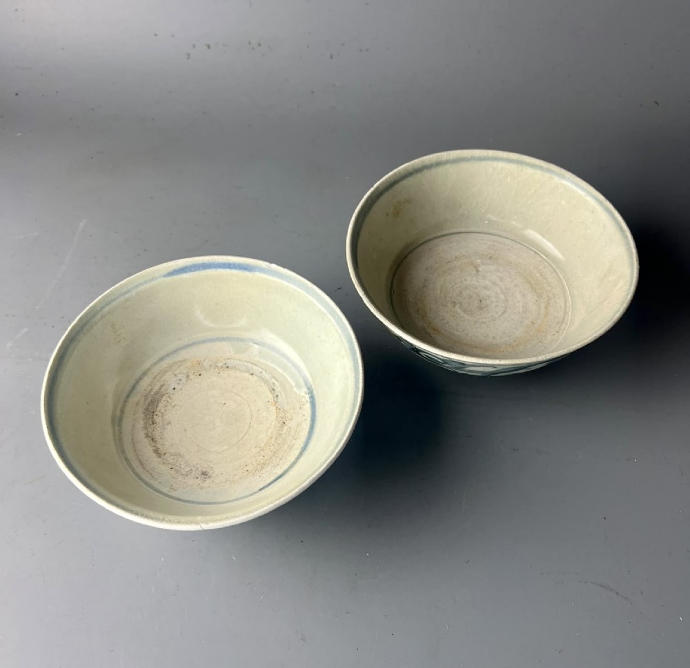 A pair of 17th-century Chinese shipwreck porcelain bowls featuring hand-painted cobalt blue swirling patterns over an off-white background. View IV