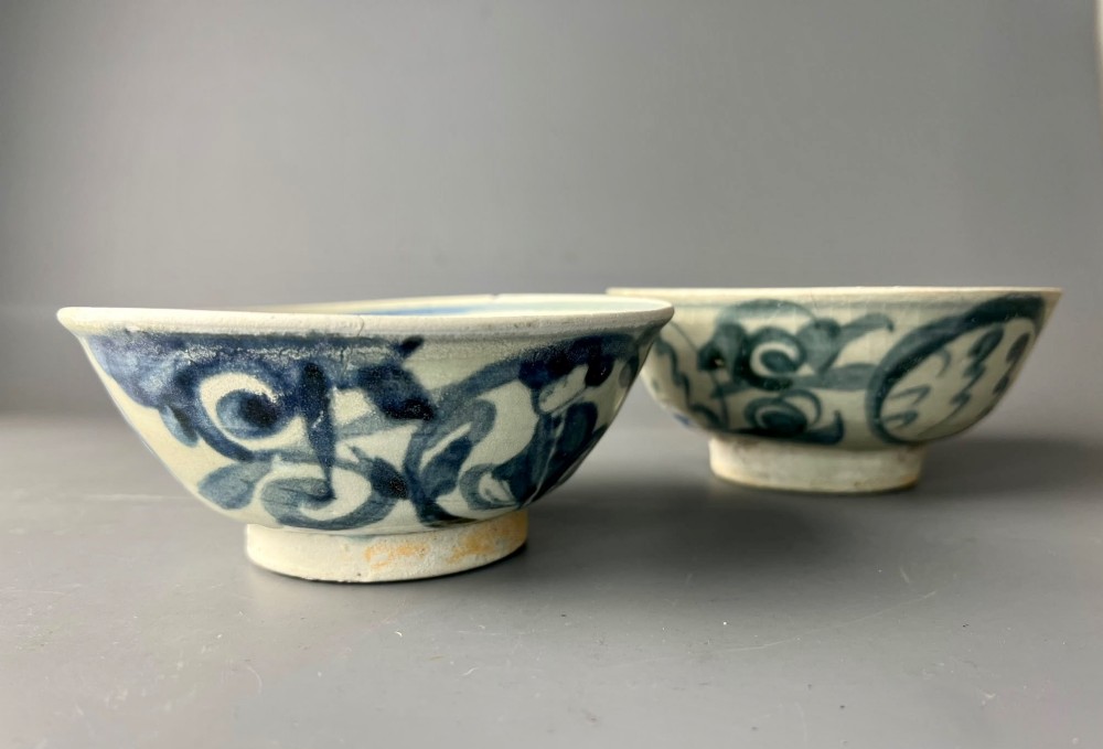 A pair of 17th-century Chinese shipwreck porcelain bowls featuring hand-painted cobalt blue swirling patterns over an off-white background. View V