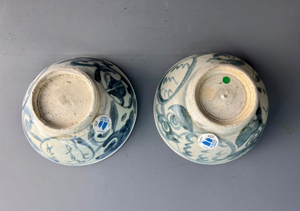 A pair of 17th-century Chinese shipwreck porcelain bowls featuring hand-painted cobalt blue swirling patterns over an off-white background. View VI