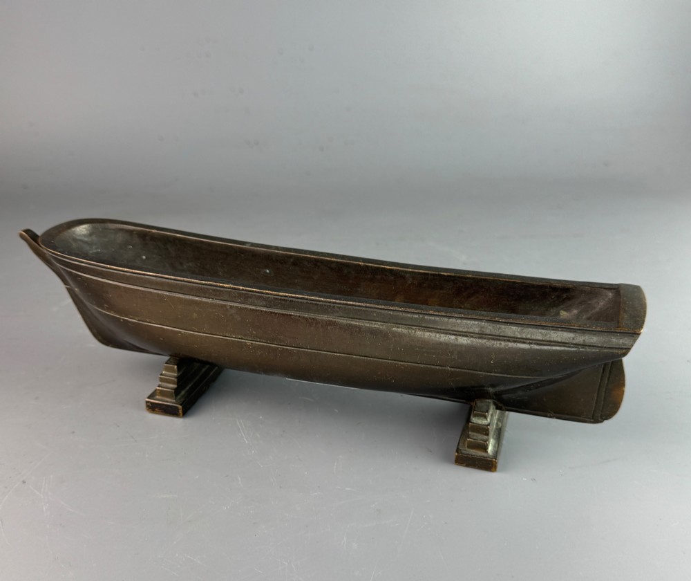An Art Deco dark bronze pen tray designed in the form of a boat hull mounted on two stepped support feet. View III