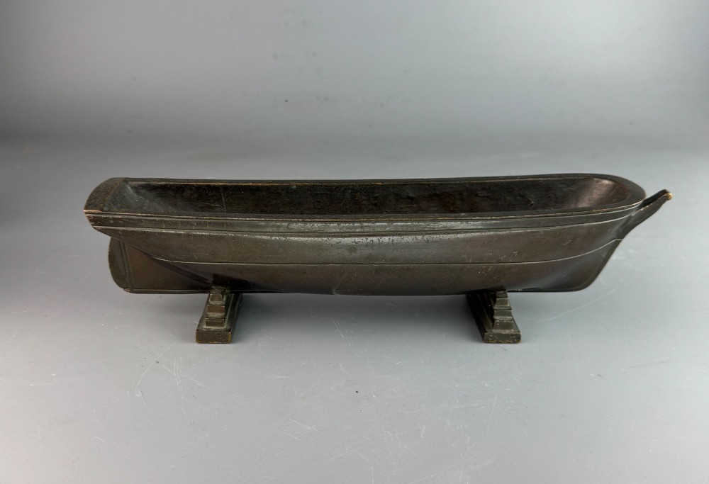 An Art Deco dark bronze pen tray designed in the form of a boat hull mounted on two stepped support feet. View V