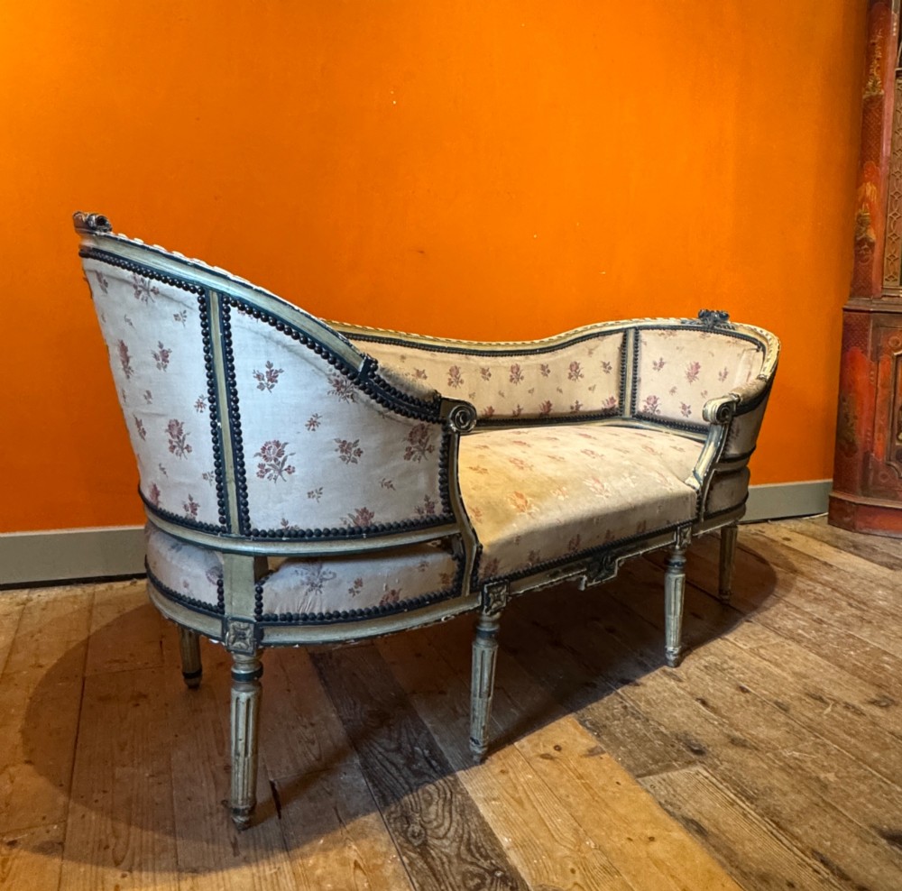 An antique French Louis XVI style duchesse brisee chaise with a distressed off-white painted wooden frame, fluted legs, and floral upholstery. View II