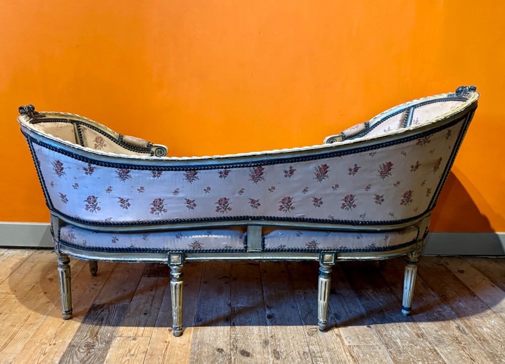 An antique French Louis XVI style duchesse brisee chaise with a distressed off-white painted wooden frame, fluted legs, and floral upholstery. View III