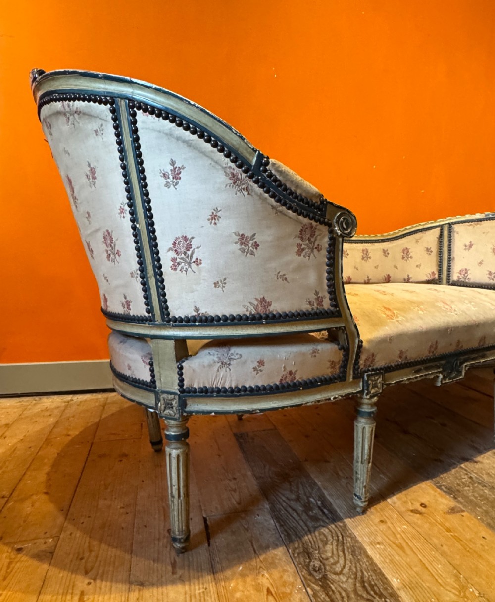 An antique French Louis XVI style duchesse brisee chaise with a distressed off-white painted wooden frame, fluted legs, and floral upholstery. View VII