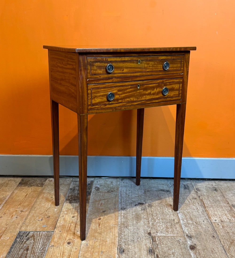 A Sheraton style satinwood side table featuring two crossbanded drawers with round brass pulls and square tapered legs. View III