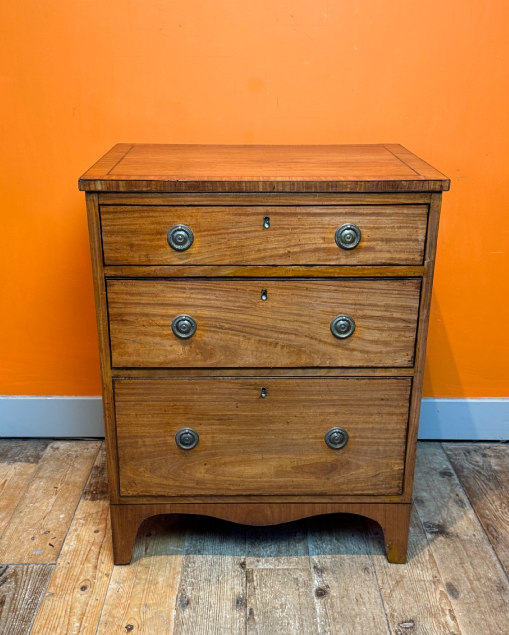 A small Regency satinwood chest of three graduated drawers with brass handles and string inlay.