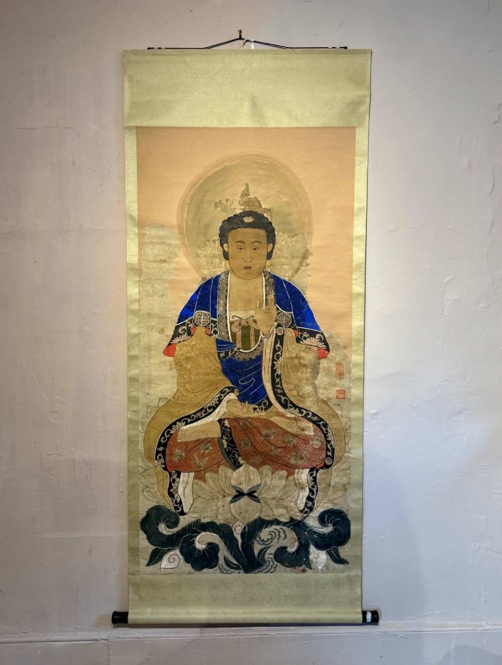 A 19th-century Chinese hanging scroll painting depicting Buddha Shakyamuni seated cross-legged on a lotus throne in blue and gold robes. View V