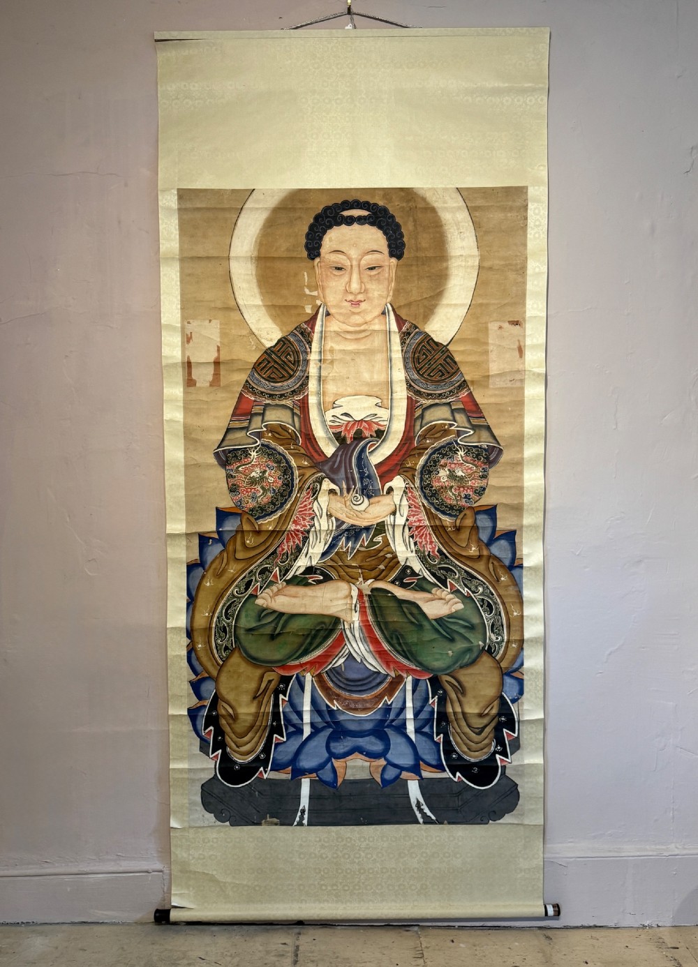 A 19th-century Chinese hanging scroll depicting Buddha Shakyamuni seated on a lotus throne painted in mineral pigments with silk mounting.