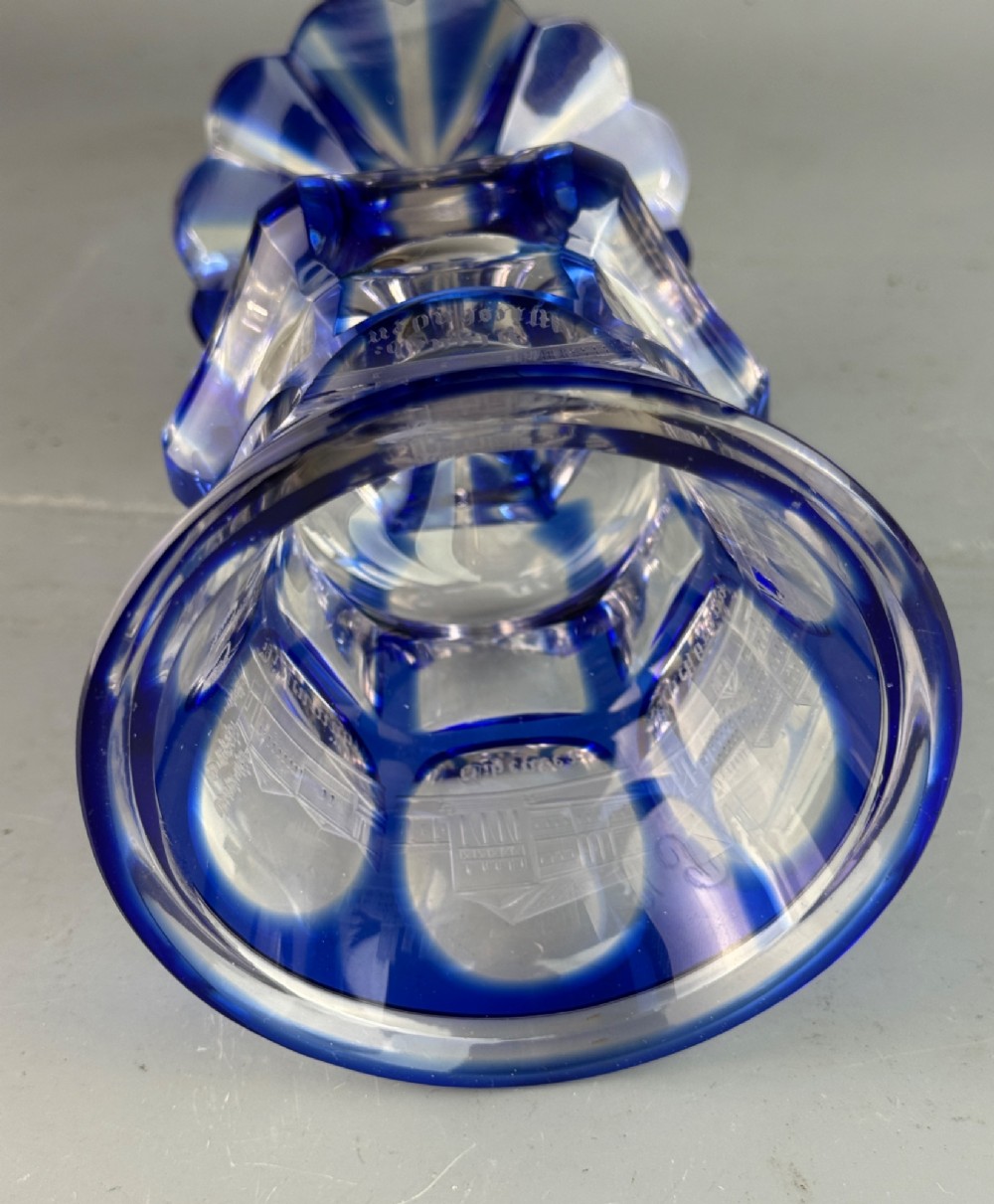 A cobalt blue cut-to-clear glass spa goblet featuring wheel-engraved architectural medallions, a faceted stem, and a starburst base. View III