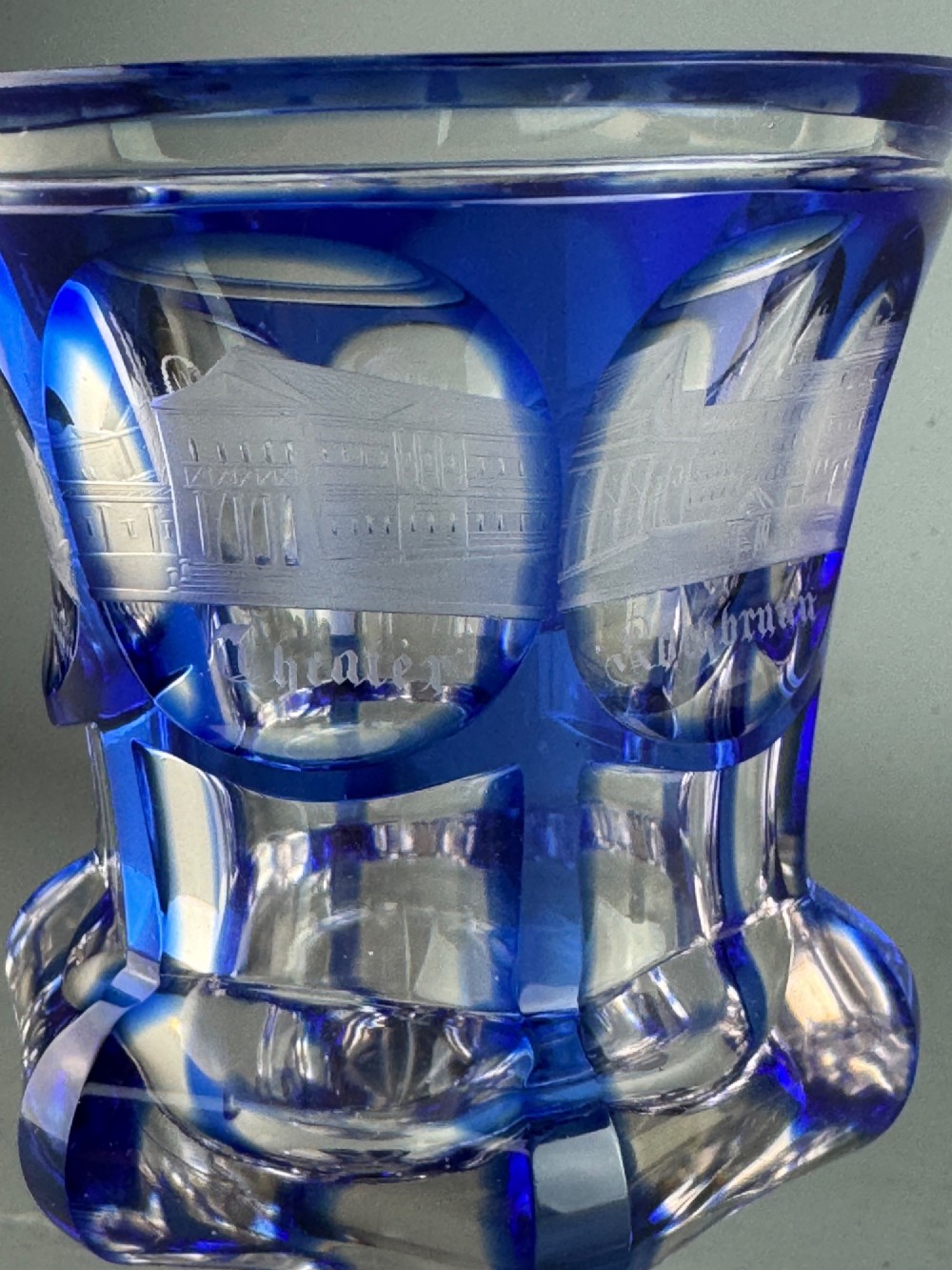 A cobalt blue cut-to-clear glass spa goblet featuring wheel-engraved architectural medallions, a faceted stem, and a starburst base. View VII