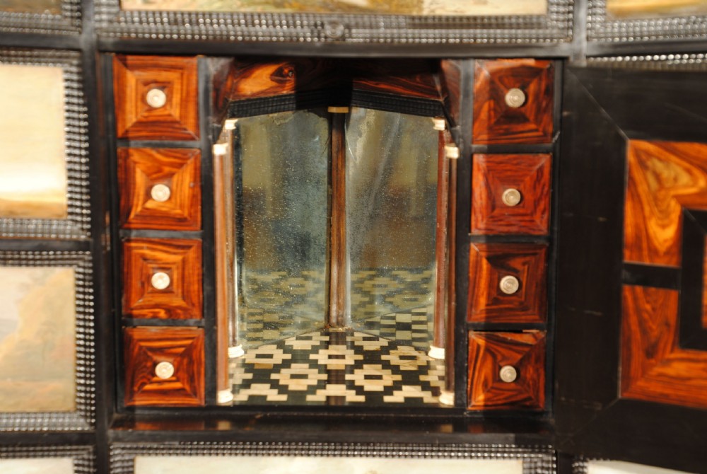 An ebonised 17th-century table cabinet with open doors and lid revealing multiple drawer fronts decorated with painted landscape scenes. View III
