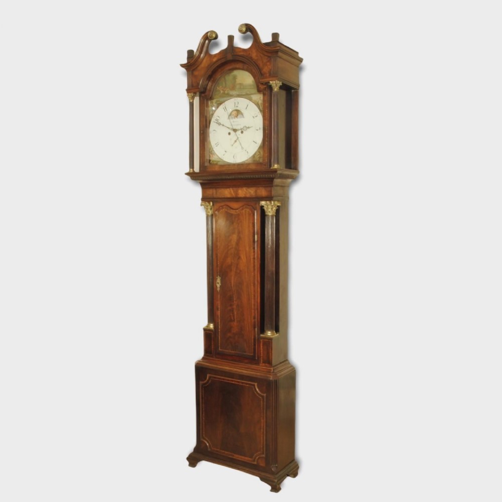 An 18th-century mahogany longcase clock featuring a swan-neck pediment, brass columns, and an arch-topped painted dial.