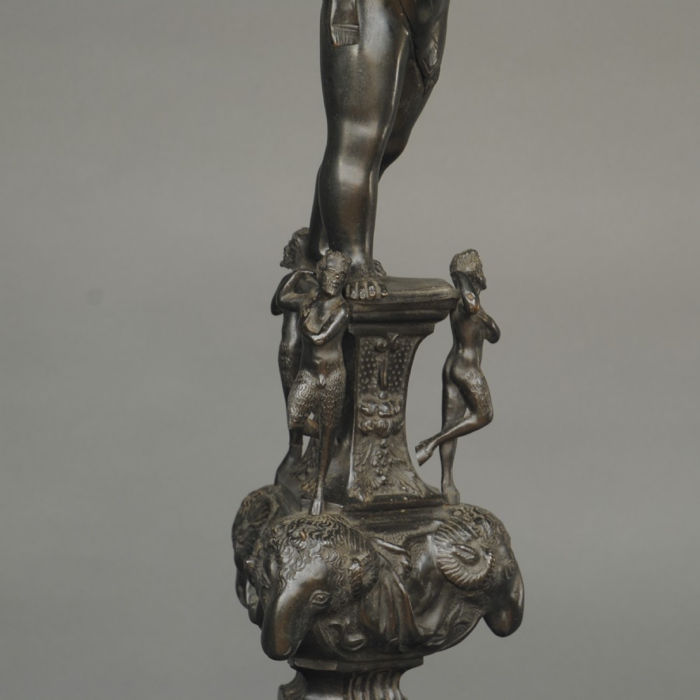 A matching pair of dark patinated bronze 19th-century Italianate andirons featuring standing cherub figures atop elaborate scrollwork and mask bases. View V