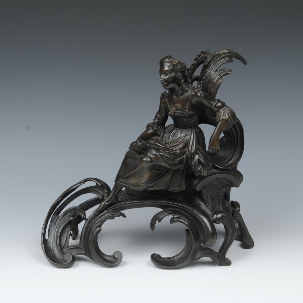 A pair of dark patinated bronze 19th-century French Rococo style chenets featuring sculpted figures seated atop elaborate scrollwork bases. View II
