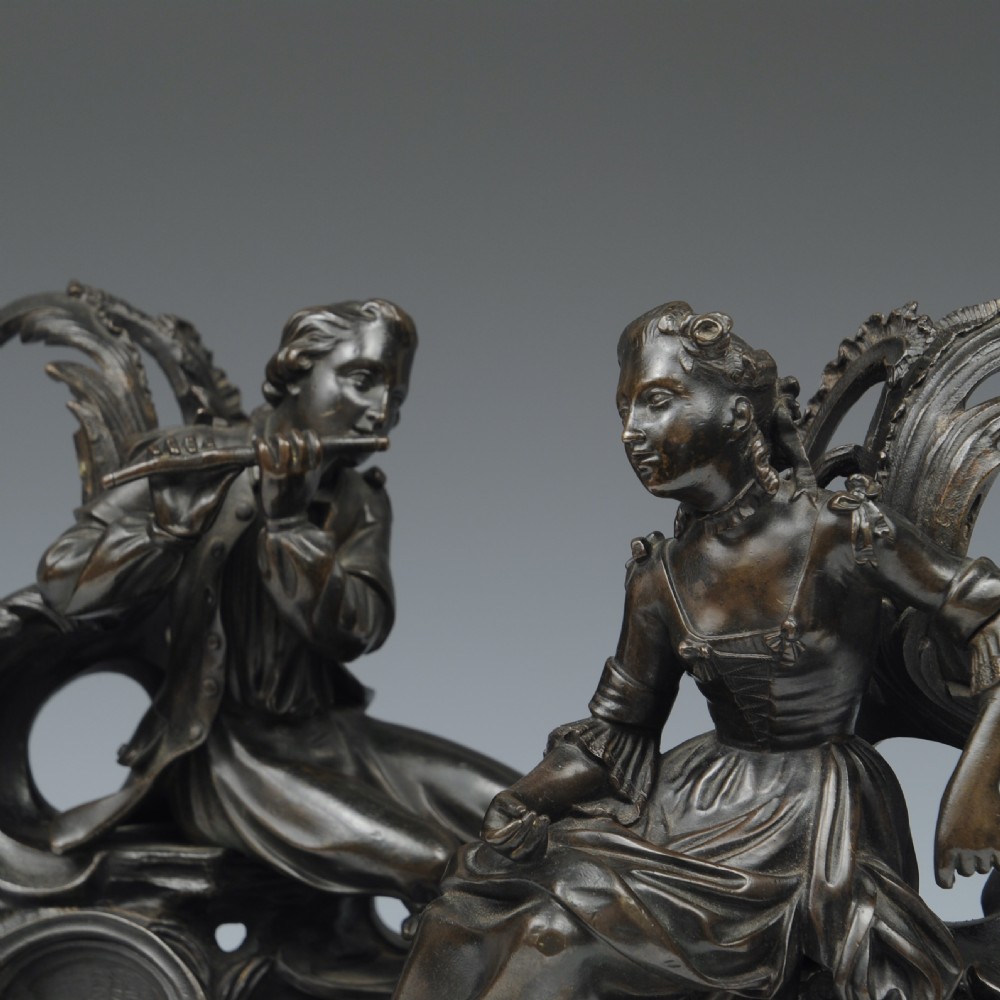 A pair of dark patinated bronze 19th-century French Rococo style chenets featuring sculpted figures seated atop elaborate scrollwork bases. View III