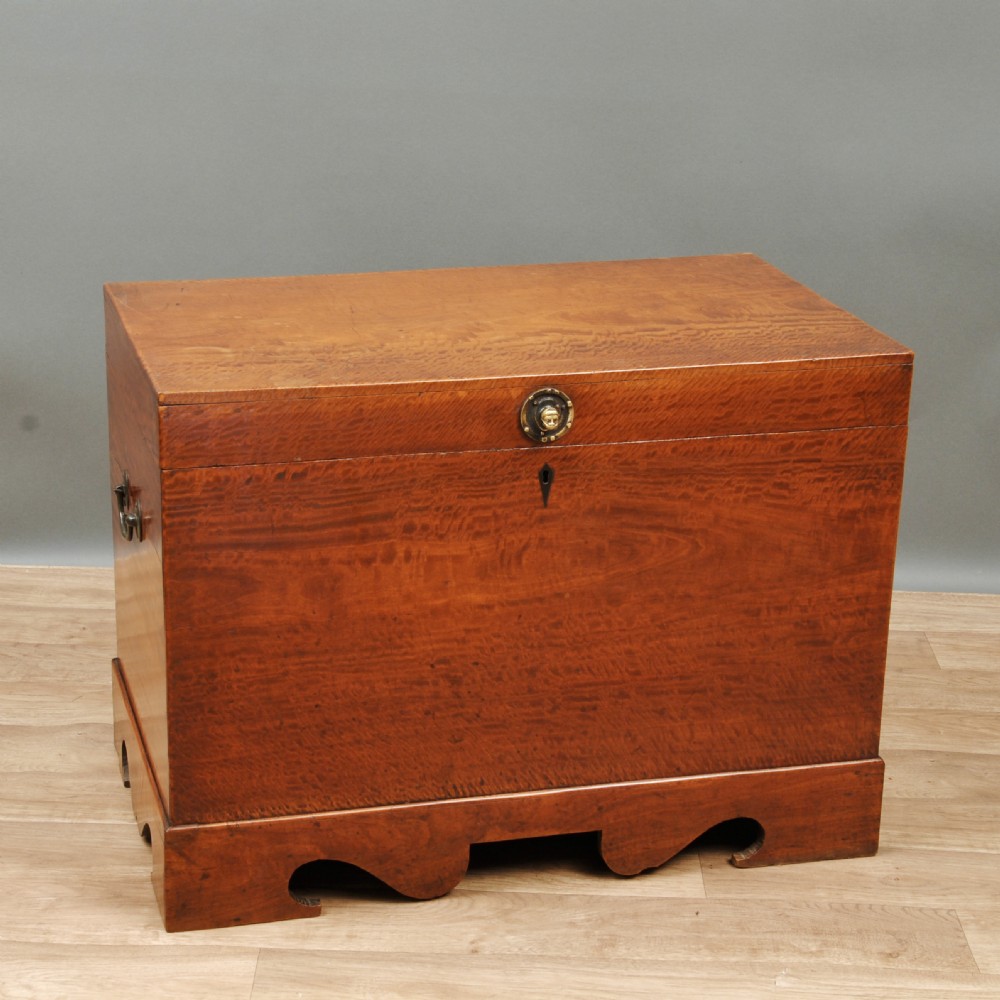 A rectangular solid satinwood colonial trunk featuring brass side handles, keyhole escutcheon, and a scalloped apron base. View IV