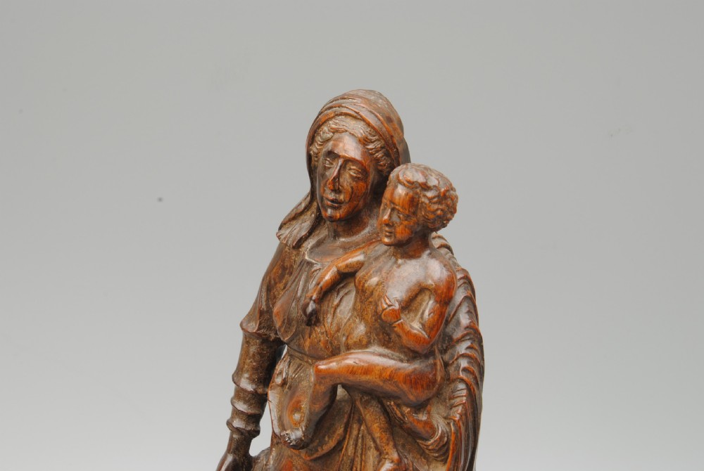 A dark hardwood carving of the Madonna standing in draped robes whilst holding the Christ child. View IV