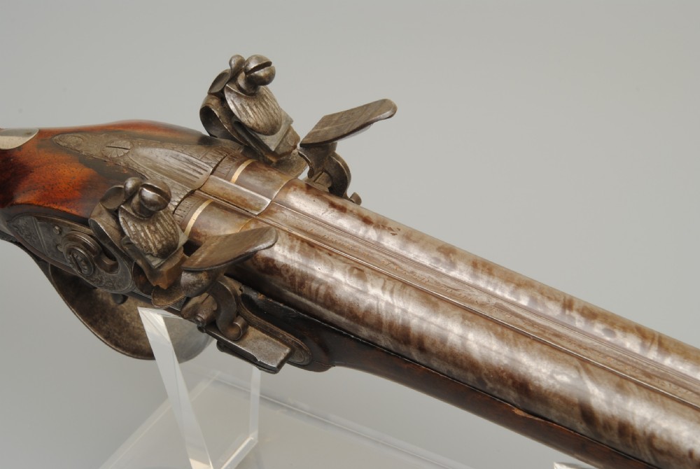 An antique double-barrel flintlock sporting gun featuring a dark walnut wood stock, twin steel barrels, and intricate lockwork. View II