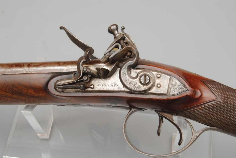 An antique double-barrel flintlock sporting gun featuring a dark walnut wood stock, twin steel barrels, and intricate lockwork. View V