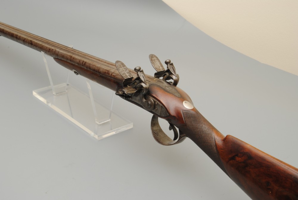 An antique double-barrel flintlock sporting gun featuring a dark walnut wood stock, twin steel barrels, and intricate lockwork. View VI