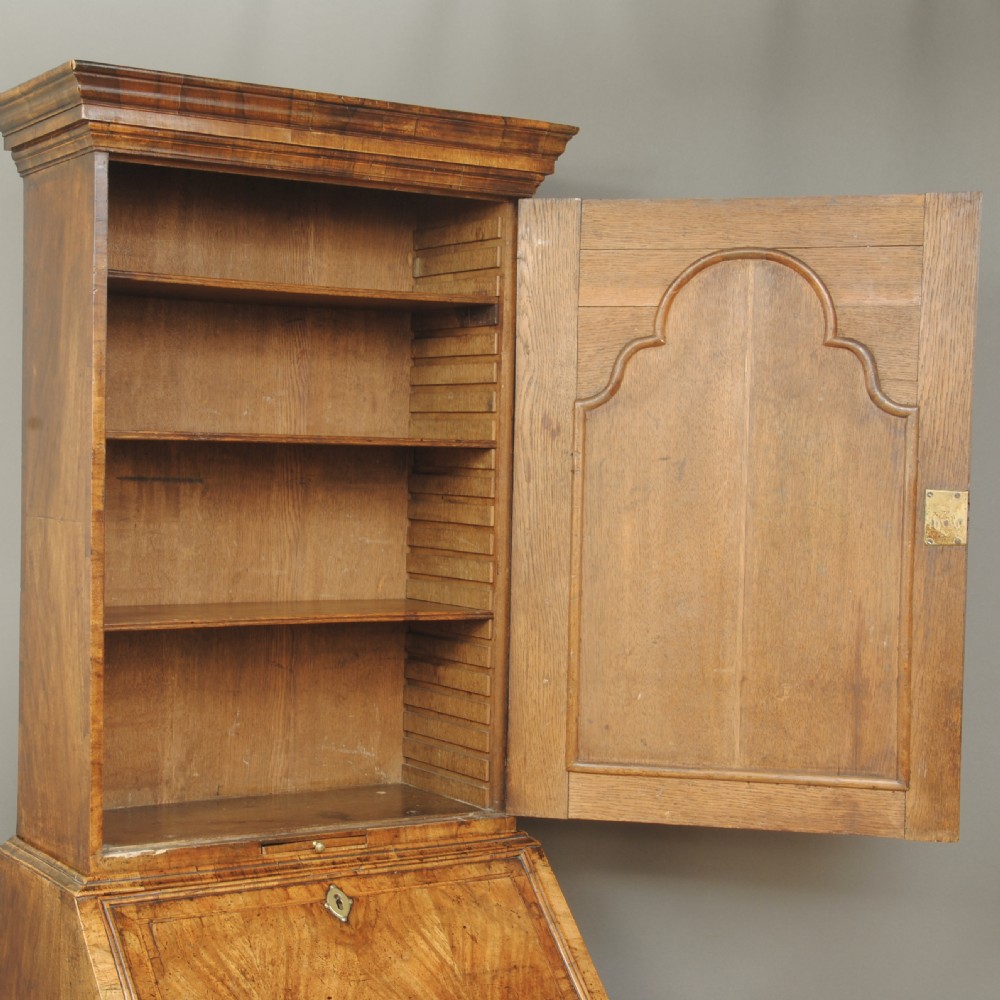 A compact Queen Anne walnut bureau bookcase featuring an arched mirror door upper section above a slant-front desk and two drawers on bun feet. View V