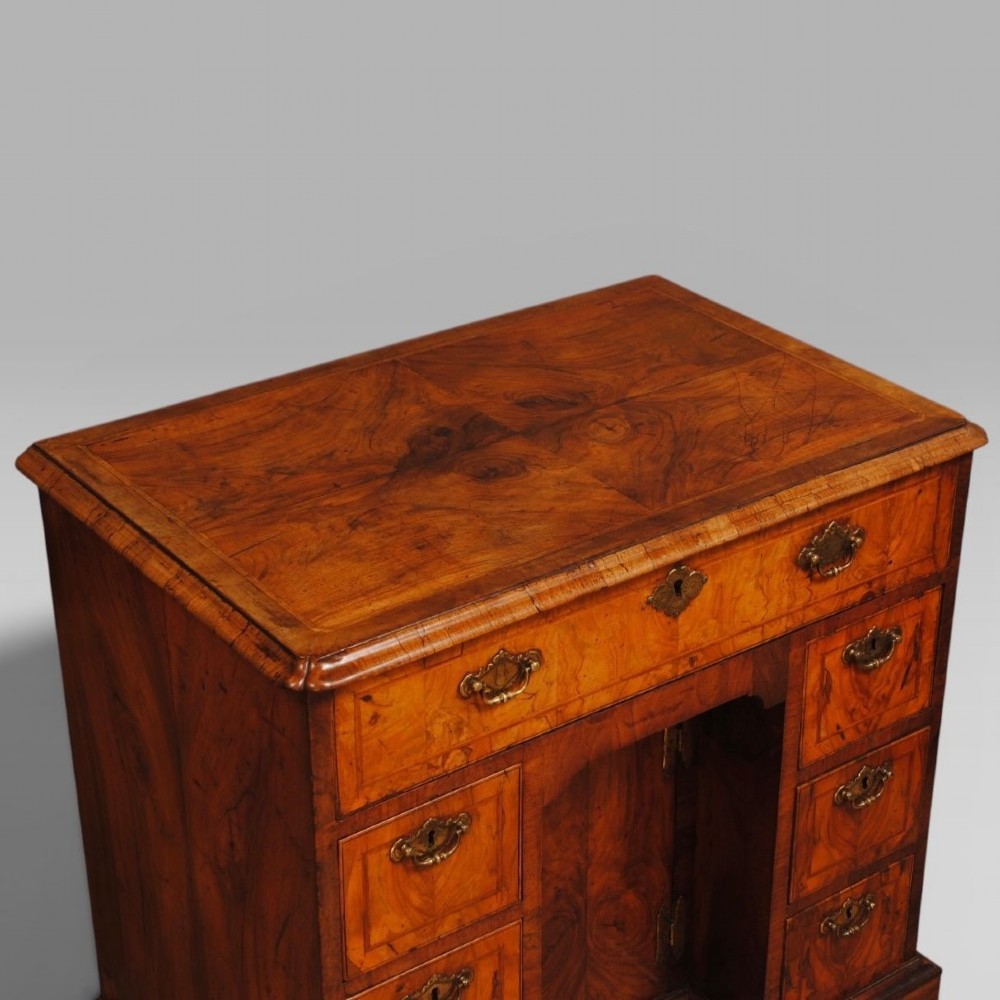 An 18th-century Queen Anne burr walnut kneehole desk featuring a long upper drawer, six side drawers, a central recessed cupboard, brass teardrop handles, and bracket feet. View III