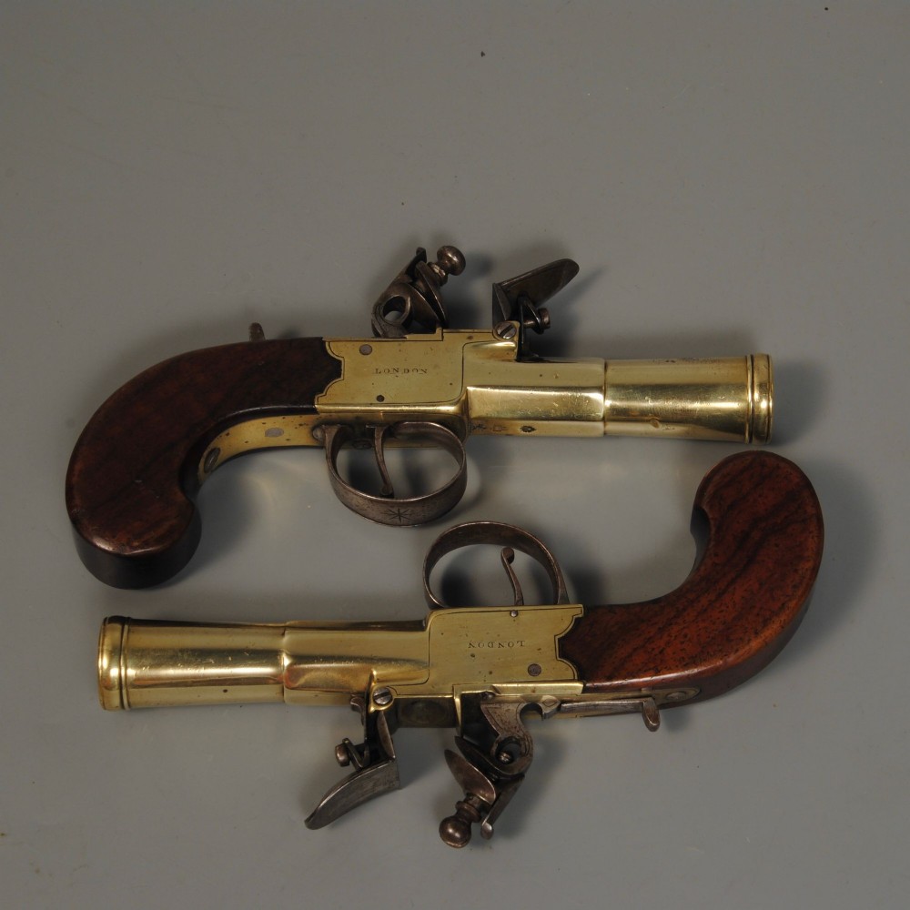 A pair of antique Georgian boxlock flintlock pistols featuring flared brass barrels, steel mechanisms, and dark wood grips. View II