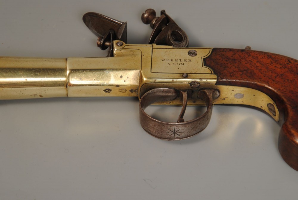 A pair of antique Georgian boxlock flintlock pistols featuring flared brass barrels, steel mechanisms, and dark wood grips. View V
