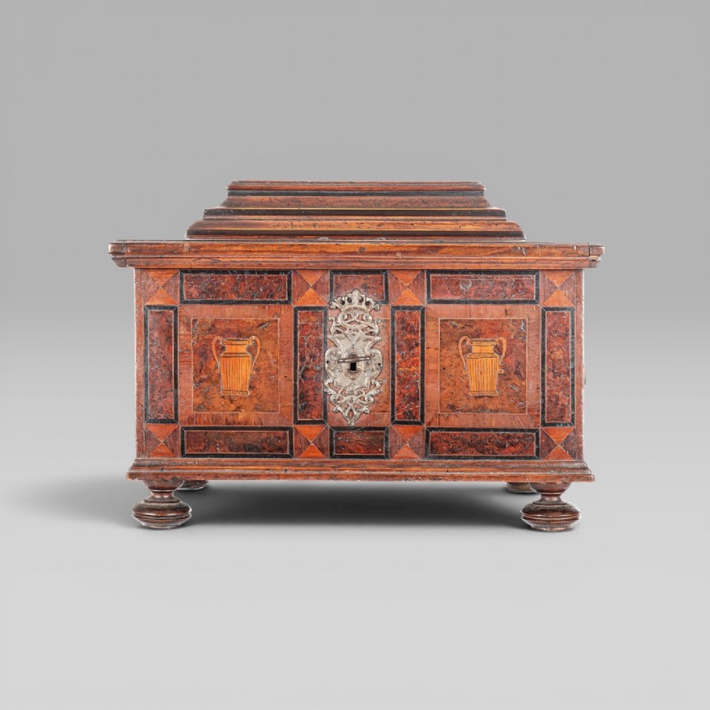A late 17th-century Continental burr wood casket with a stepped lid, inlaid urn motifs, side iron handles, and a decorative keyhole escutcheon resting on bun feet. View II