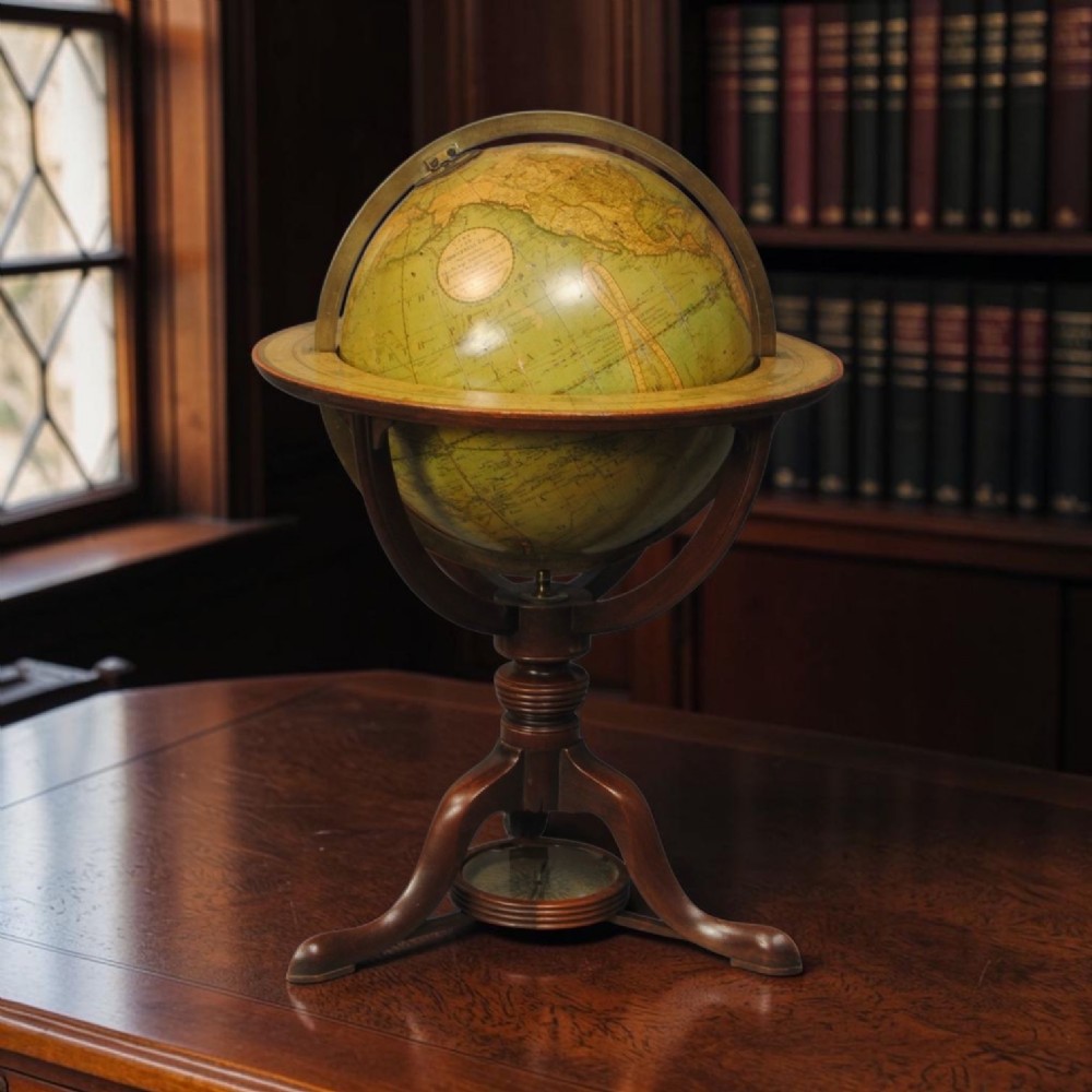 An early nineteenth-century terrestrial table globe supported by a turned mahogany tripod stand with a brass meridian ring and an integrated base compass. View V