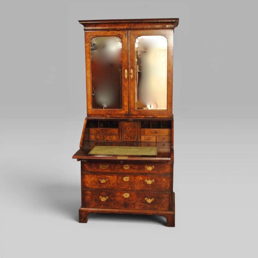 Queen Anne burr walnut bureau bookcase featuring upper double arched mirrored doors above a slant-front writing desk and graduated lower drawers with brass handles. View II