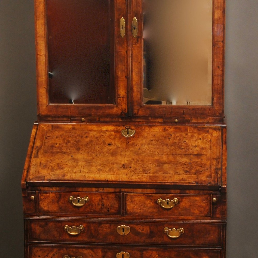 Queen Anne burr walnut bureau bookcase featuring upper double arched mirrored doors above a slant-front writing desk and graduated lower drawers with brass handles. View III