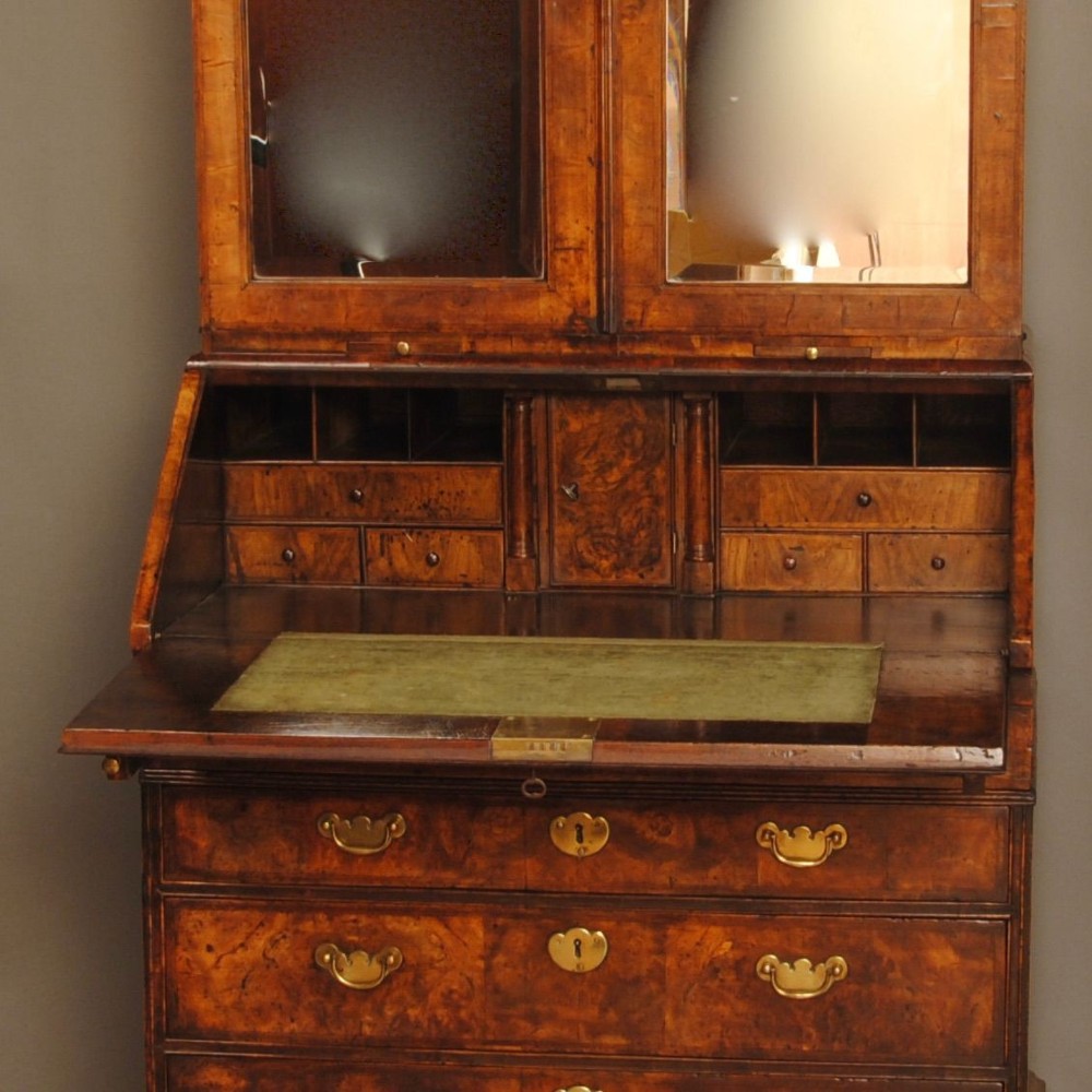 Queen Anne burr walnut bureau bookcase featuring upper double arched mirrored doors above a slant-front writing desk and graduated lower drawers with brass handles. View IV