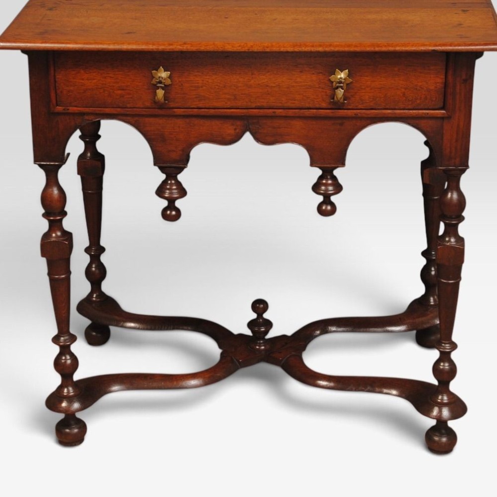 An eighteenth-century Queen Anne oak lowboy featuring turned legs, a single drawer with brass pulls, a shaped apron with drop finials, and a curved X-stretcher. View III