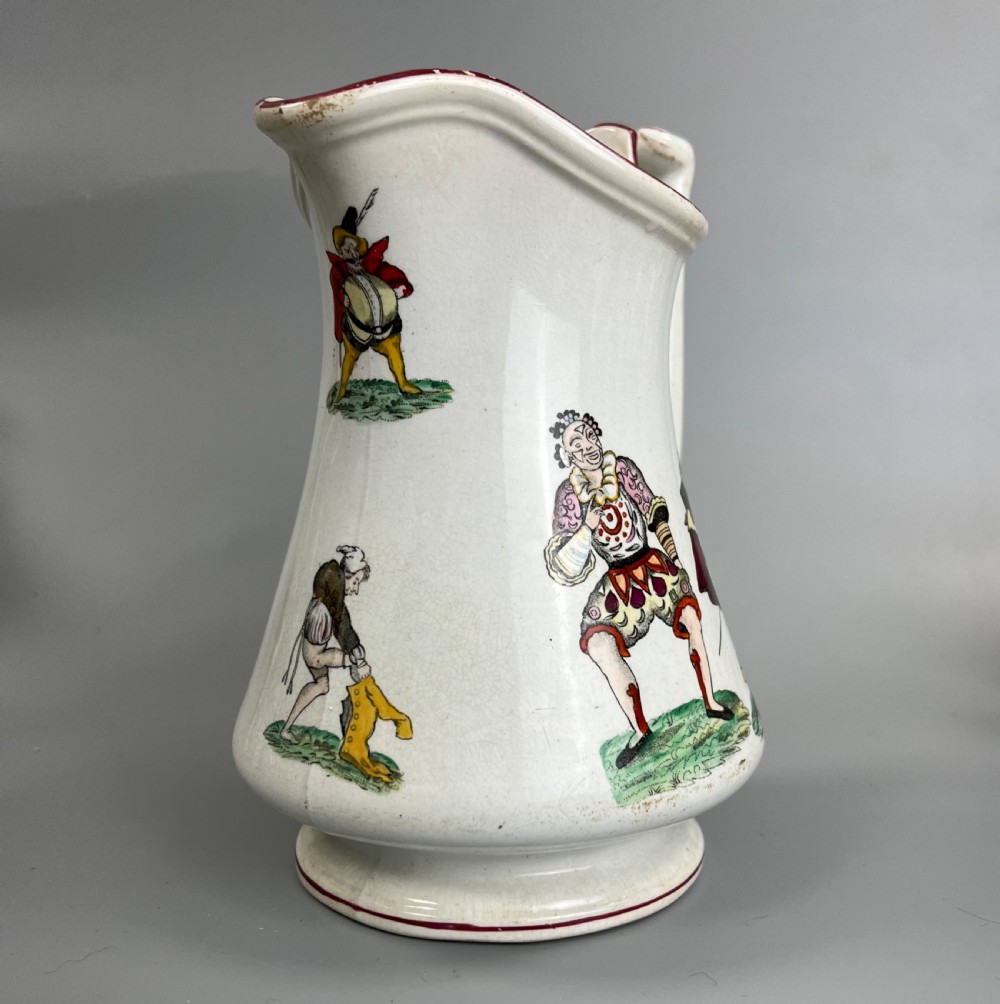 A cream earthenware ceramic jug decorated with hand-coloured transfer prints of circus performers and clowns with a red painted rim.