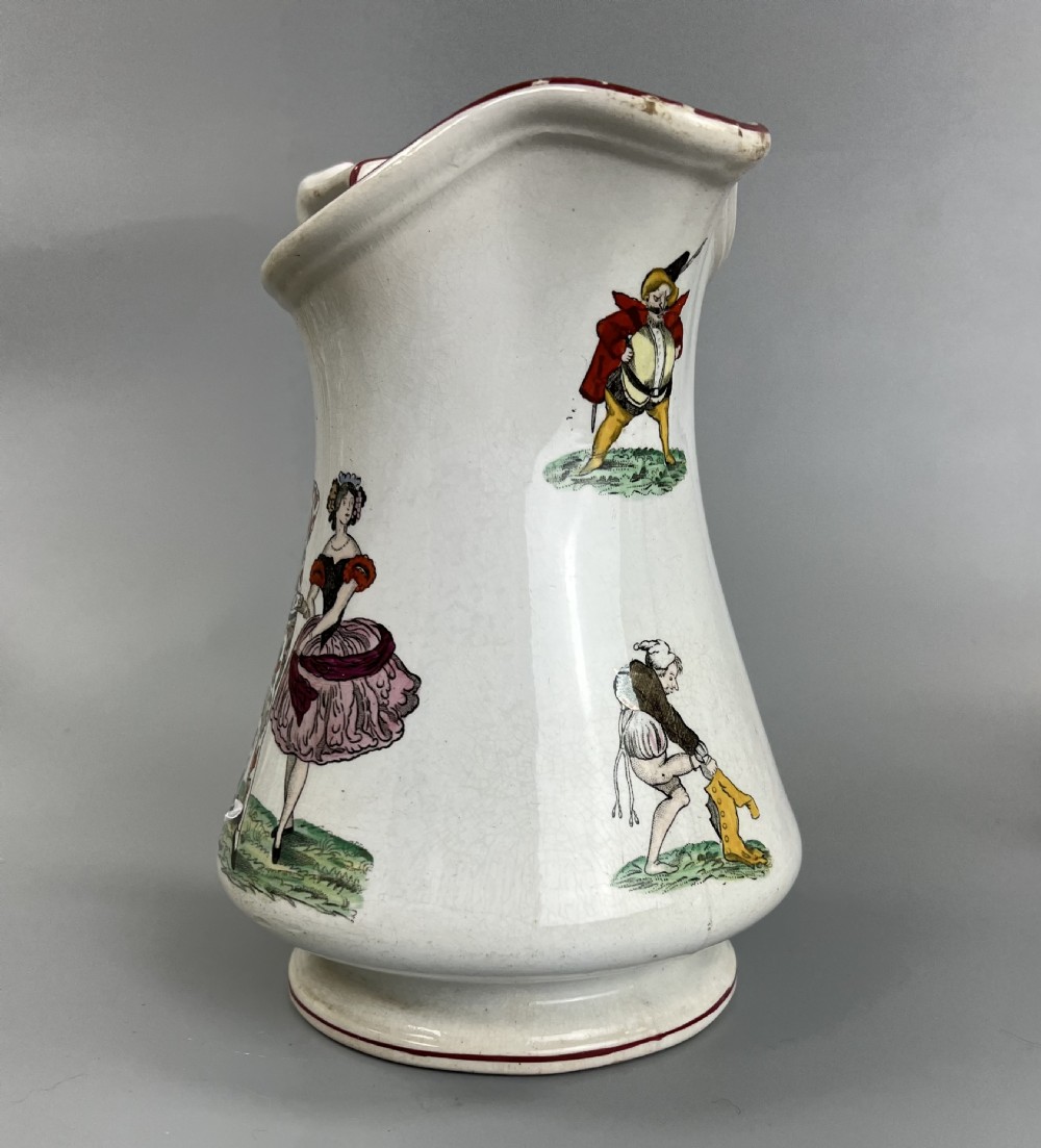 A cream earthenware ceramic jug decorated with hand-coloured transfer prints of circus performers and clowns with a red painted rim. View III